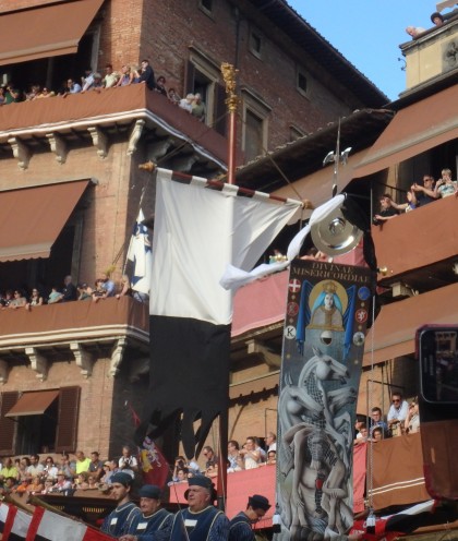 The Palio banner makes its way around the Piazza. Contrada members wave their fazzoletti as it passes them.